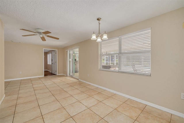 empty room featuring tile patterned flooring, ceiling fan with notable chandelier, and baseboards