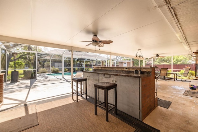 view of patio / terrace with a ceiling fan, glass enclosure, fence, and outdoor dry bar