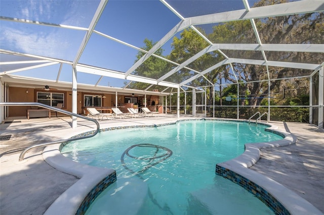 pool with a patio, glass enclosure, and a ceiling fan