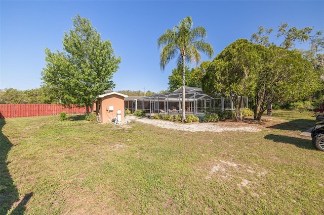 view of yard with an outdoor structure, glass enclosure, fence, and a storage unit