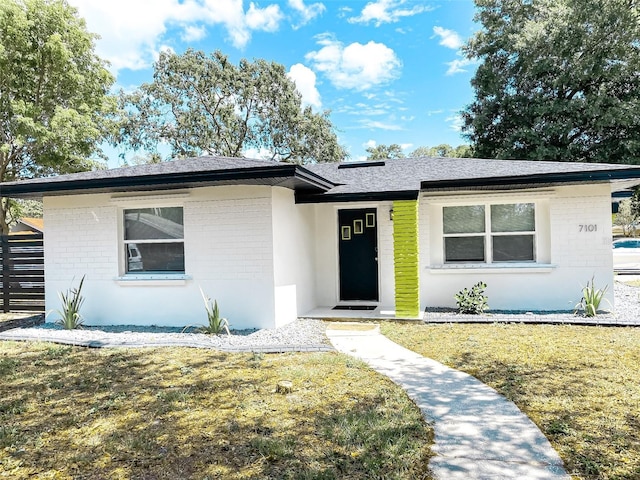 7101 N 9th St, Tampa, FL 33604 - view of front of home featuring brick siding, a front yard, and roof with shingles