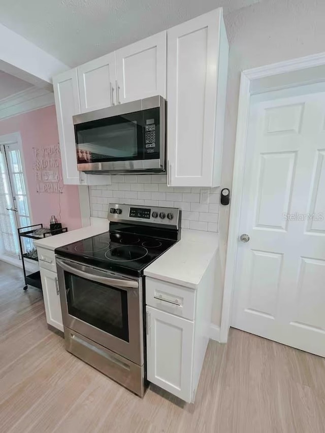 7101 N 9th St, Tampa, FL 33604 - kitchen with stainless steel appliances, light wood finished floors, light countertops, backsplash, and white cabinets