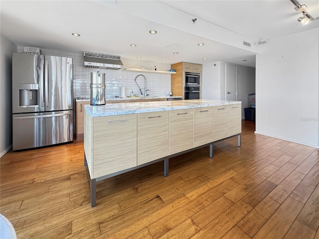kitchen with light wood-type flooring, a sink, range hood, and appliances with stainless steel finishes