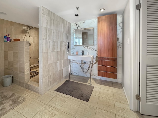 bathroom with tile walls, walk in shower, and a sink