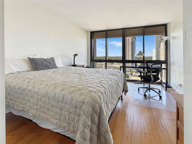 bedroom with wood-type flooring and a wall of windows