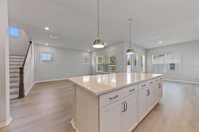 5001 21st Ave N, Saint Petersburg, FL 33710 - kitchen with light wood-style flooring, open floor plan, a center island, white cabinets, and light countertops