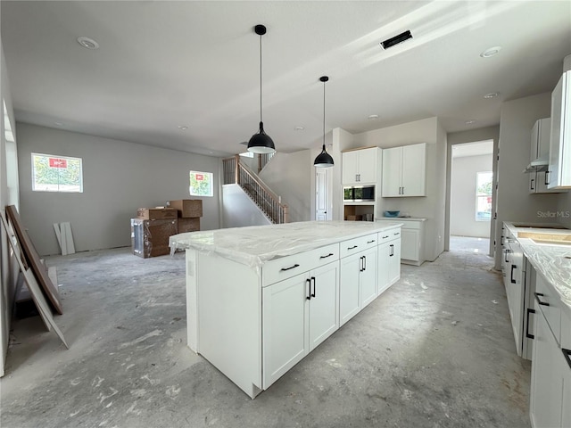 5001 21st Ave N, Saint Petersburg, FL 33710 - kitchen with healthy amount of natural light, unfinished concrete flooring, and white cabinetry