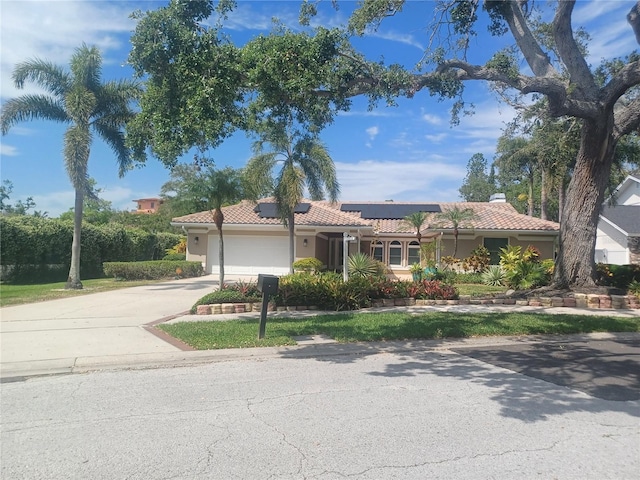 view of front of property featuring concrete driveway, a tiled roof, an attached garage, stucco siding, and solar panels