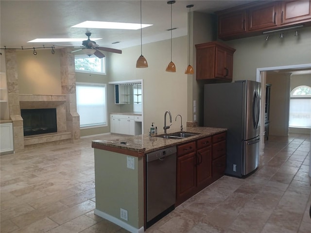 kitchen featuring a sink, stone counters, freestanding refrigerator, a ceiling fan, and dishwashing machine
