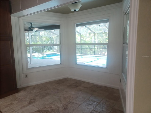 unfurnished room featuring a sunroom, a wealth of natural light, and a ceiling fan