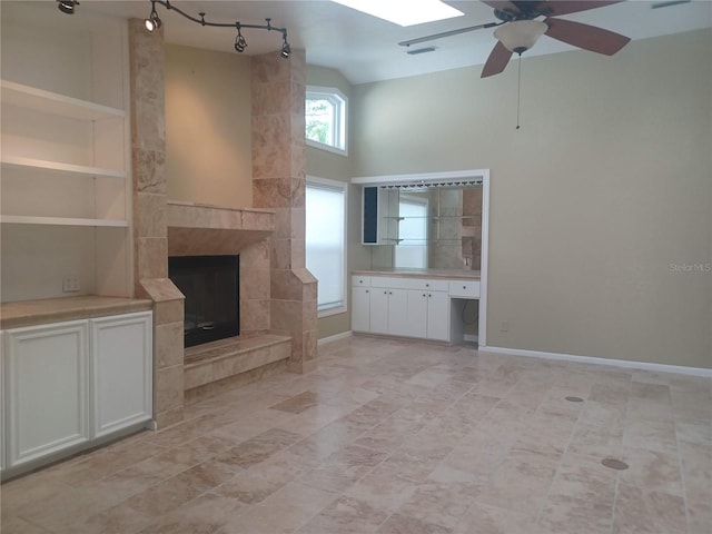 unfurnished living room featuring a tiled fireplace, visible vents, baseboards, a ceiling fan, and high vaulted ceiling
