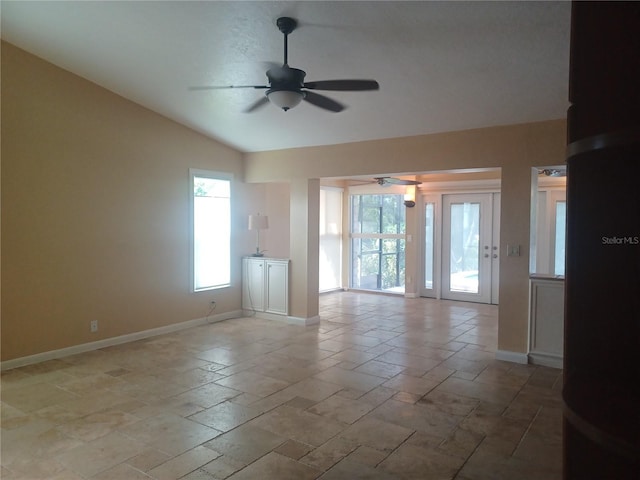 unfurnished room with lofted ceiling, a ceiling fan, baseboards, and stone tile flooring