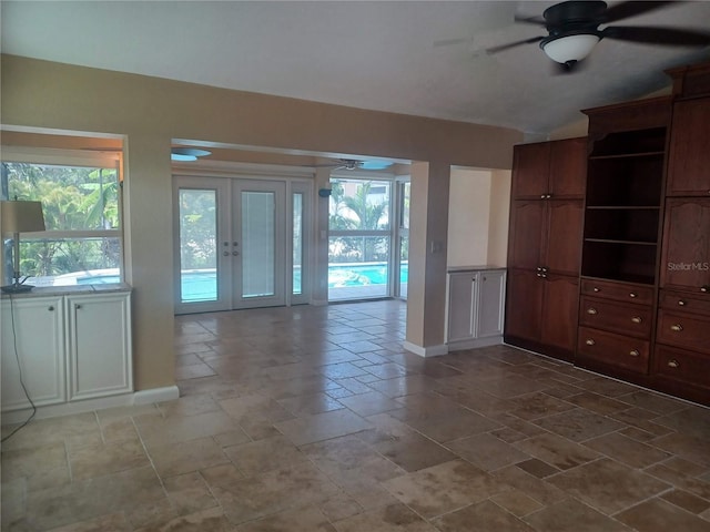 unfurnished living room with french doors, a ceiling fan, baseboards, and vaulted ceiling