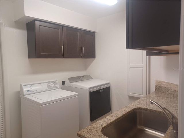 washroom with cabinet space, a sink, and washer and clothes dryer