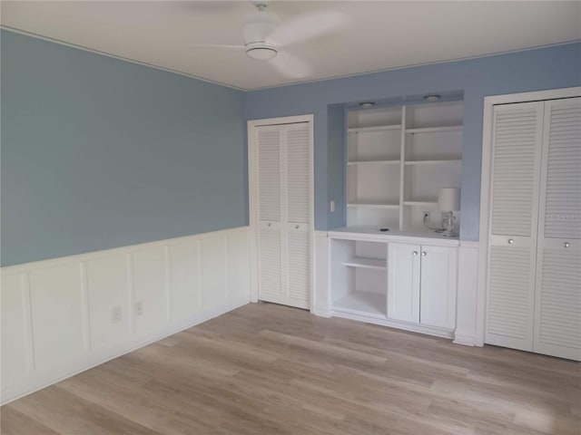 unfurnished dining area with a wainscoted wall and light wood-style flooring