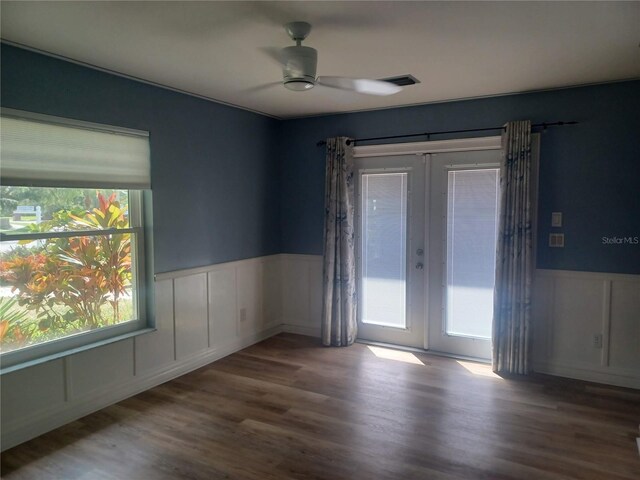 spare room featuring french doors, a wainscoted wall, wood finished floors, ceiling fan, and a decorative wall