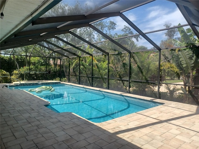 outdoor pool featuring glass enclosure and a patio