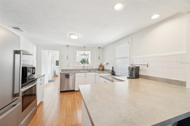 3611 4th Ave N, Saint Petersburg, FL 33713 - kitchen featuring visible vents, a sink, a peninsula, white cabinetry, and stainless steel appliances