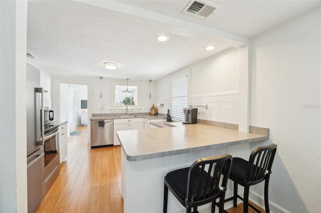 3611 4th Ave N, Saint Petersburg, FL 33713 - kitchen with a peninsula, white cabinetry, visible vents, a breakfast bar area, and stainless steel dishwasher