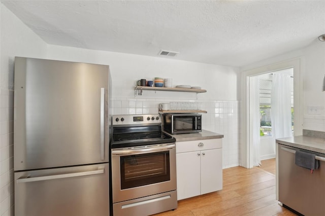 3611 4th Ave N, Saint Petersburg, FL 33713 - kitchen featuring a textured ceiling, white cabinetry, visible vents, stainless steel appliances, and light wood finished floors
