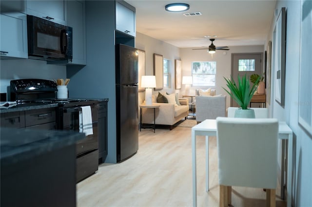 kitchen featuring visible vents, open floor plan, ceiling fan, black appliances, and light wood-style flooring