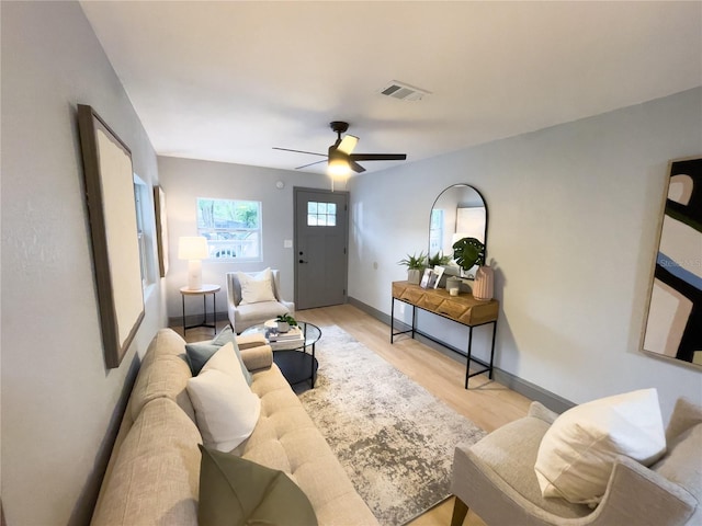 living area featuring visible vents, ceiling fan, baseboards, and wood finished floors