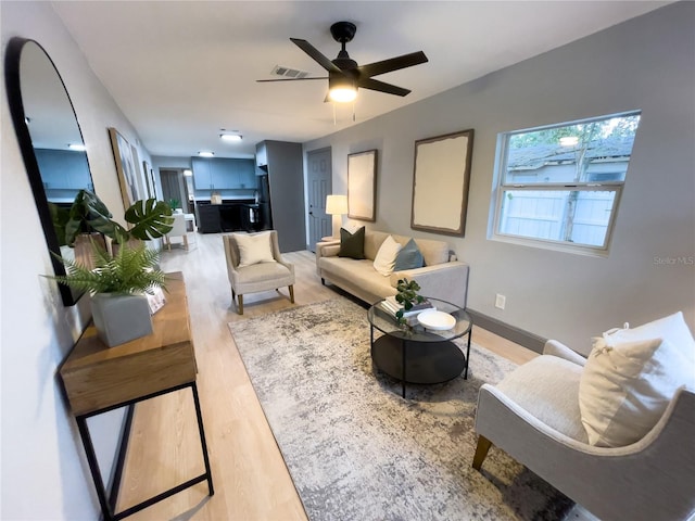 living area featuring light wood-type flooring, ceiling fan, baseboards, and visible vents