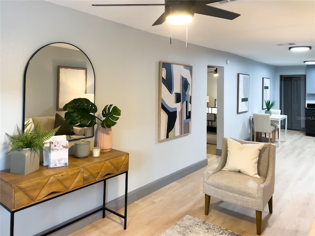 living area featuring light wood-style flooring, baseboards, a ceiling fan, and visible vents
