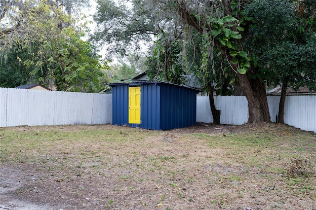 view of yard with a shed, a fenced backyard, and an outbuilding