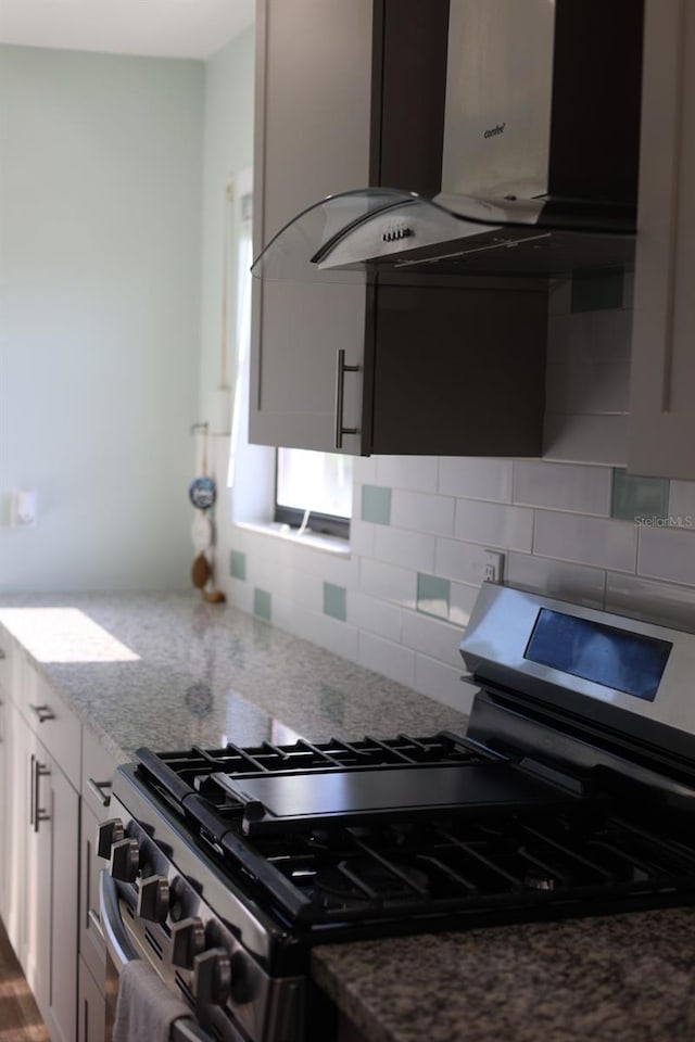 5973 Terrace Park Dr N Unit 311, Saint Petersburg, FL 33709 - kitchen featuring stainless steel range with gas cooktop, island range hood, backsplash, and light stone countertops