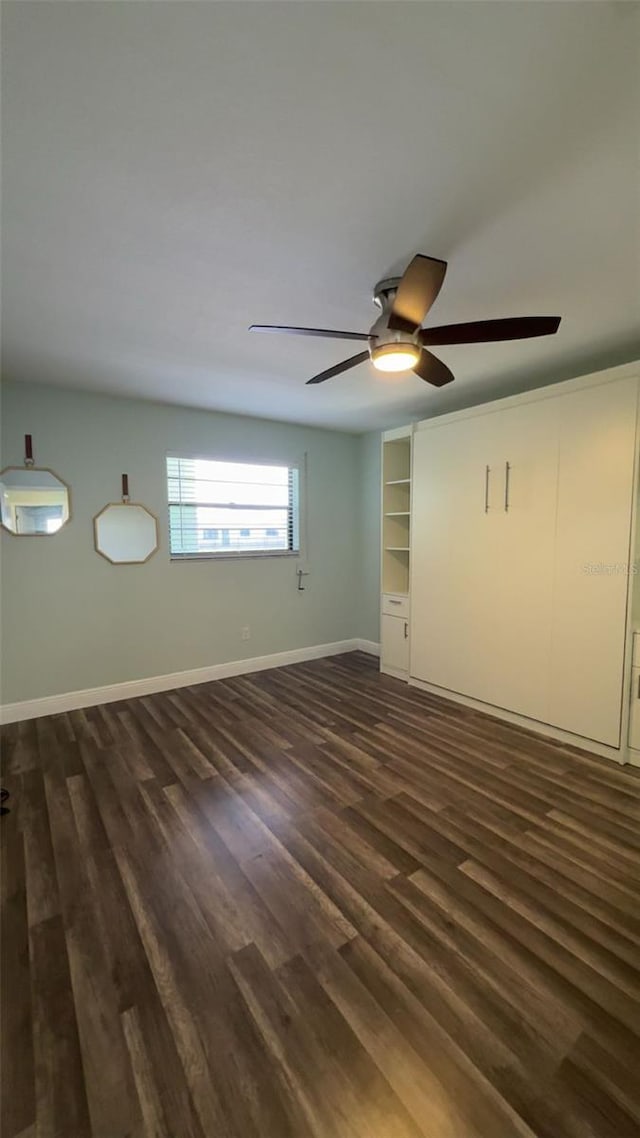 5973 Terrace Park Dr N Unit 311, Saint Petersburg, FL 33709 - unfurnished bedroom featuring dark wood-type flooring, baseboards, and a ceiling fan