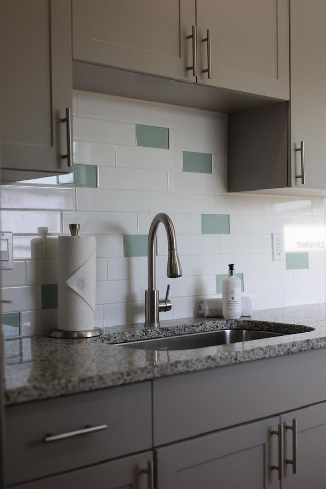 5973 Terrace Park Dr N Unit 311, Saint Petersburg, FL 33709 - details featuring gray cabinets, light stone counters, and backsplash