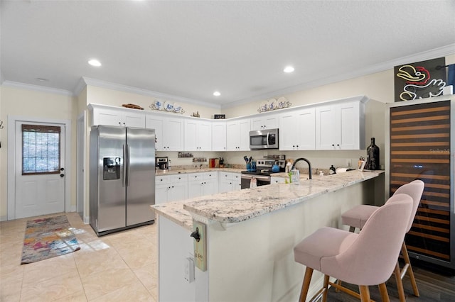 1410 25th St N, Saint Petersburg, FL 33713 - kitchen featuring crown molding, white cabinets, a peninsula, appliances with stainless steel finishes, and light stone countertops