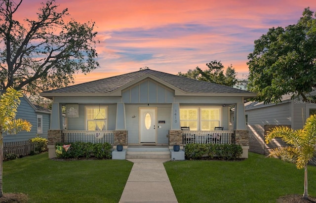 1410 25th St N, Saint Petersburg, FL 33713 - bungalow-style house featuring a lawn, a shingled roof, stone siding, and covered porch