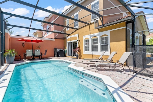 outdoor pool featuring glass enclosure and a patio