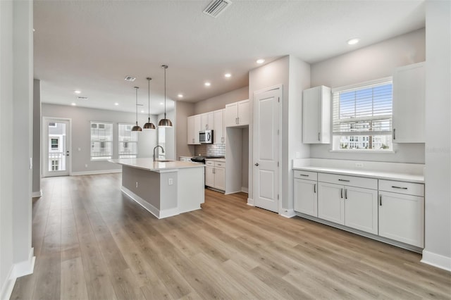 445 31st Way N, Saint Petersburg, FL 33713 - kitchen featuring visible vents, a sink, baseboards, stainless steel microwave, and light wood finished floors