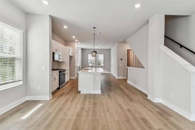 445 31st Way N, Saint Petersburg, FL 33713 - kitchen with light wood-type flooring, a sink, white cabinets, stainless steel microwave, and gas range oven
