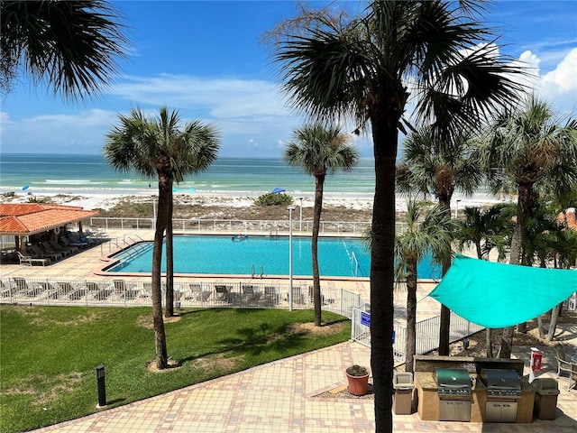 community pool with a patio, an outdoor kitchen, grilling area, a yard, and fence
