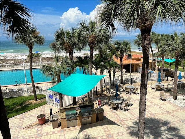 view of pool with area for grilling, grilling area, fence, and a water view