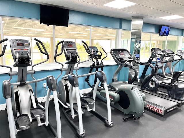 gym featuring a paneled ceiling and baseboards