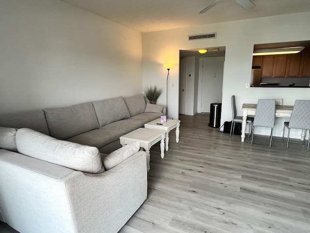 living area with visible vents, ceiling fan, and light wood-style flooring