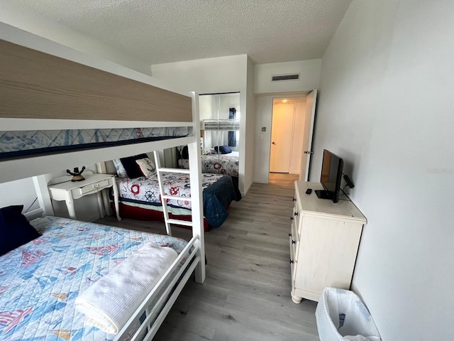 bedroom with visible vents, light wood-type flooring, and a textured ceiling