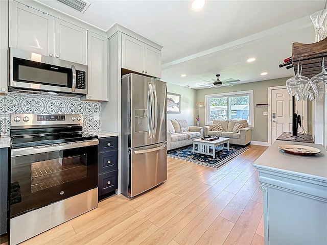 kitchen with ceiling fan, light wood-type flooring, light countertops, appliances with stainless steel finishes, and open floor plan