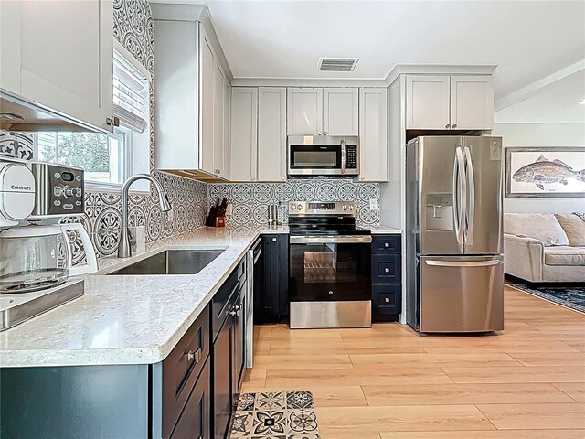 kitchen featuring a sink, stainless steel appliances, visible vents, light wood-style flooring, and light countertops