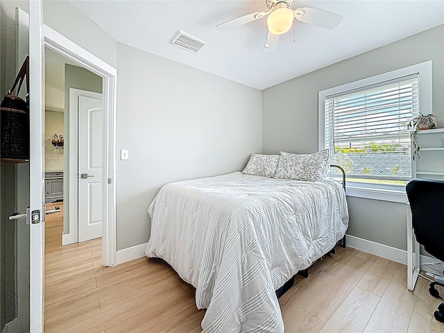 bedroom featuring baseboards, visible vents, a ceiling fan, and light wood-style flooring