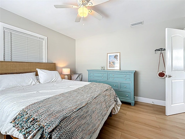 bedroom featuring light wood finished floors, a ceiling fan, visible vents, and baseboards