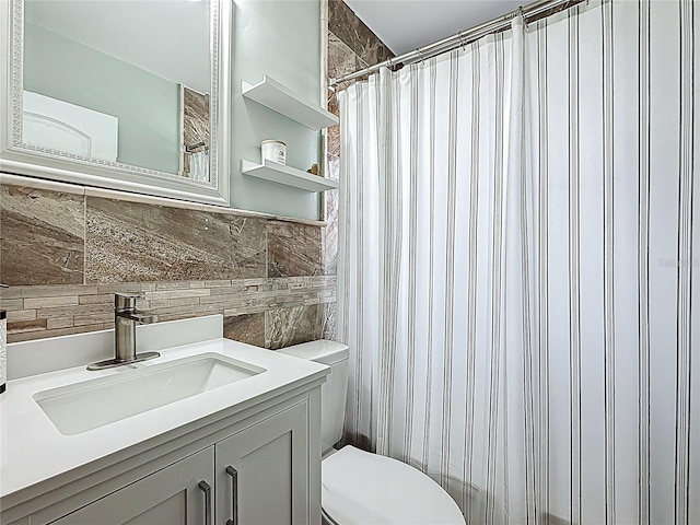 full bathroom with tile walls, curtained shower, toilet, and vanity