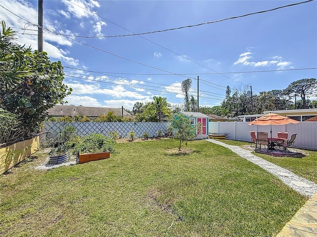 view of yard featuring an outdoor structure, a fenced backyard, a shed, and a garden