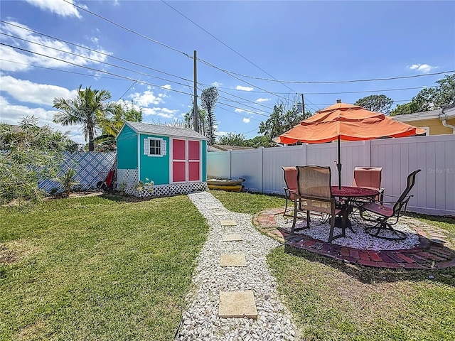view of yard with an outdoor structure, a fenced backyard, a shed, and a patio area