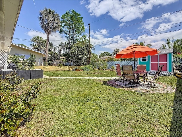 view of yard featuring an outbuilding, a patio, a shed, and fence
